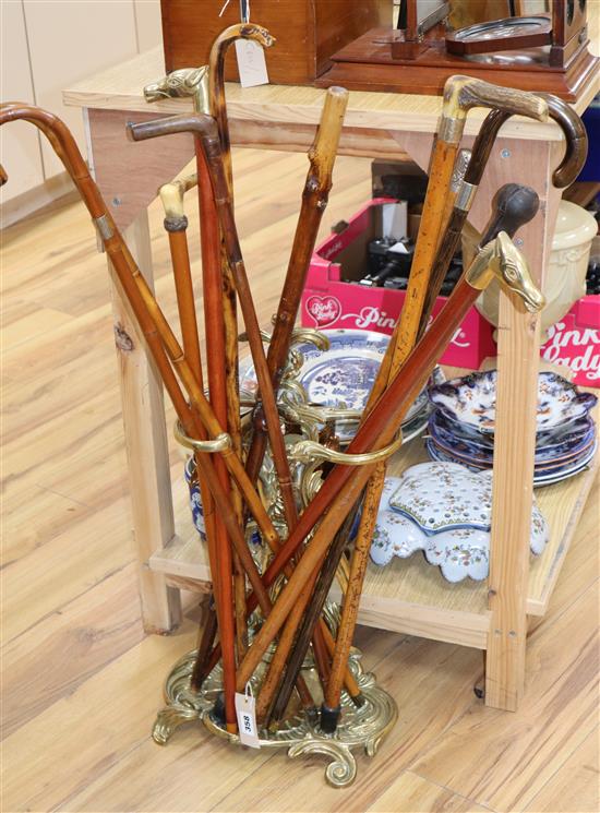 A group of walking sticks and canes, including a sword stick c.1900 and a Chinese silver topped cane, with a brass stick stand